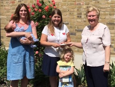 tn Maxine Blades hands over the cheque to Lactation Consultant Hannah Croft, watched by others. 