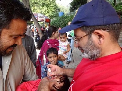 PDG Shehzad Ahmed administers a polio vaccine drop to a child at a polio camp during an immunisation day in Pakistan